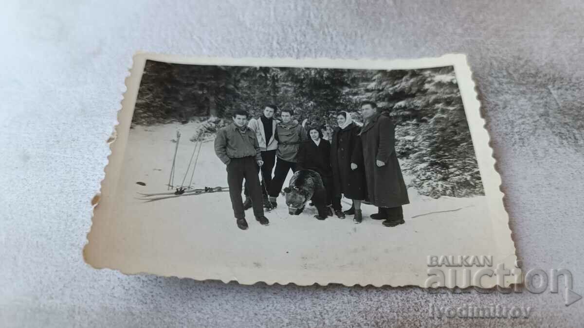Photo Men and women with a bear in the snow in the mountains
