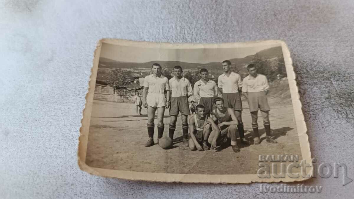 Fotografie Tineri în echipament sportiv cu o minge de fotbal de epocă