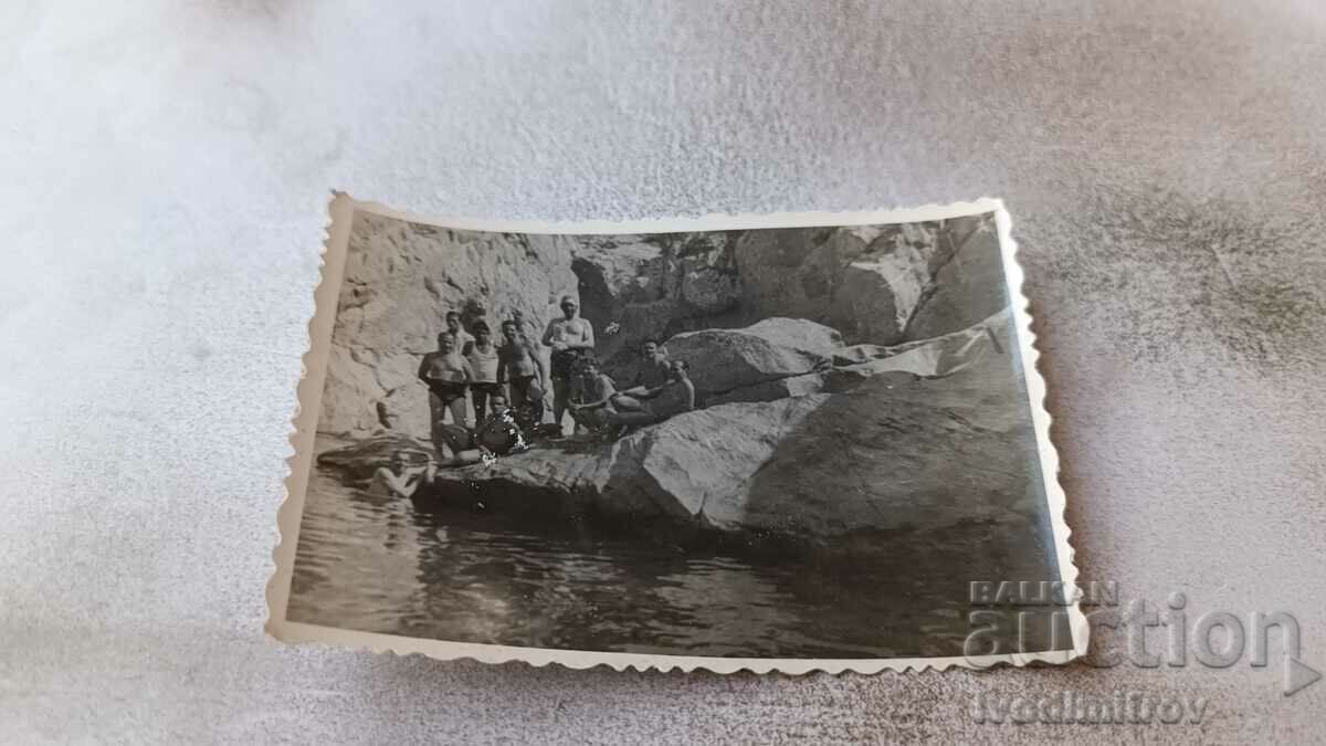 Photo Men in swimsuits on rocks by the river