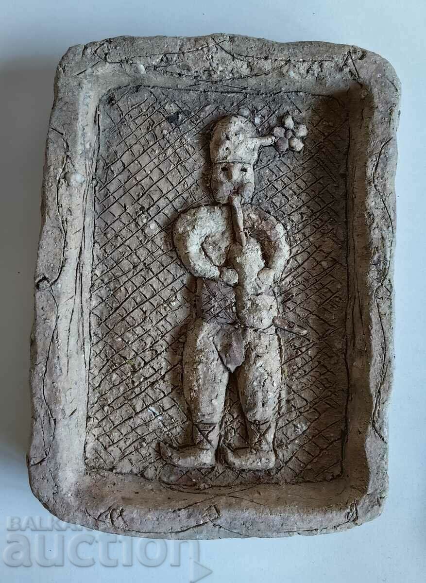 AN OLD CERAMIC PANEL OF A BASICIAN IN COSTUME