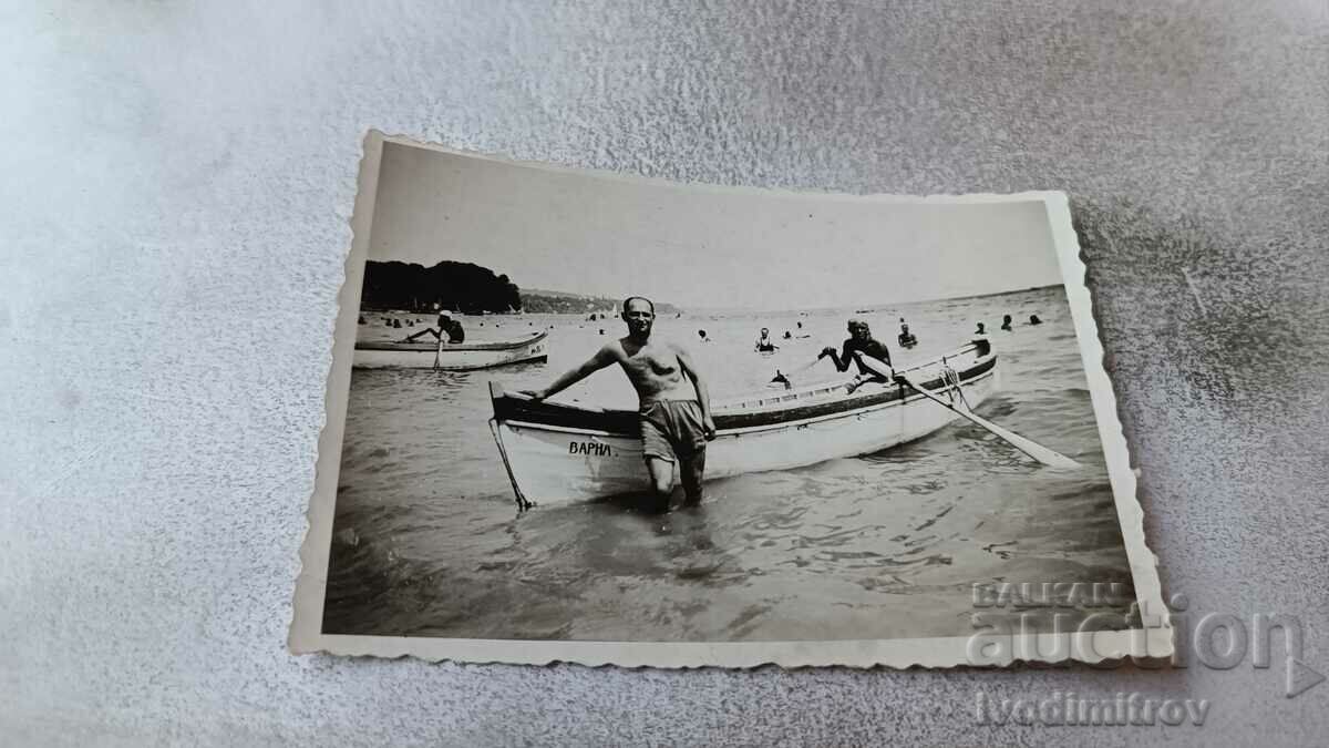 Photo A man in a swimsuit next to a VARNA boat in the sea