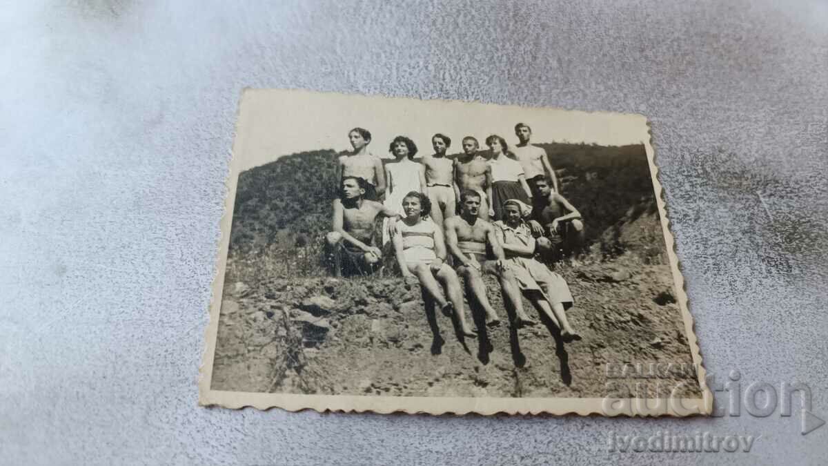 Photo Rebrovo Young men and women sitting on a rock above the river