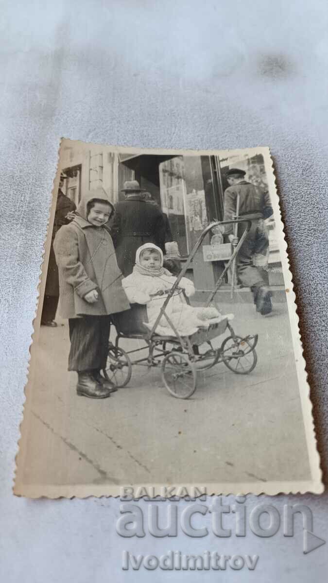 Doamna Sofia Fată și bebeluș într-un cărucior de epocă pe trotuar