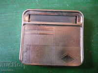 An old snuffbox with a cigarette rolling machine