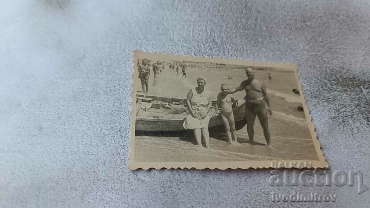 Φωτογραφία Άνδρας, γυναίκα και αγόρι δίπλα σε μια βάρκα στην παραλία 1949