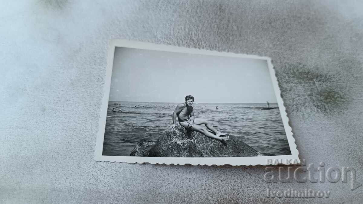 Photo Young man in a swimsuit on a rock by the sea
