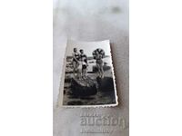 Foto Trei femei și doi copii în costume de baie pe pietre în mare