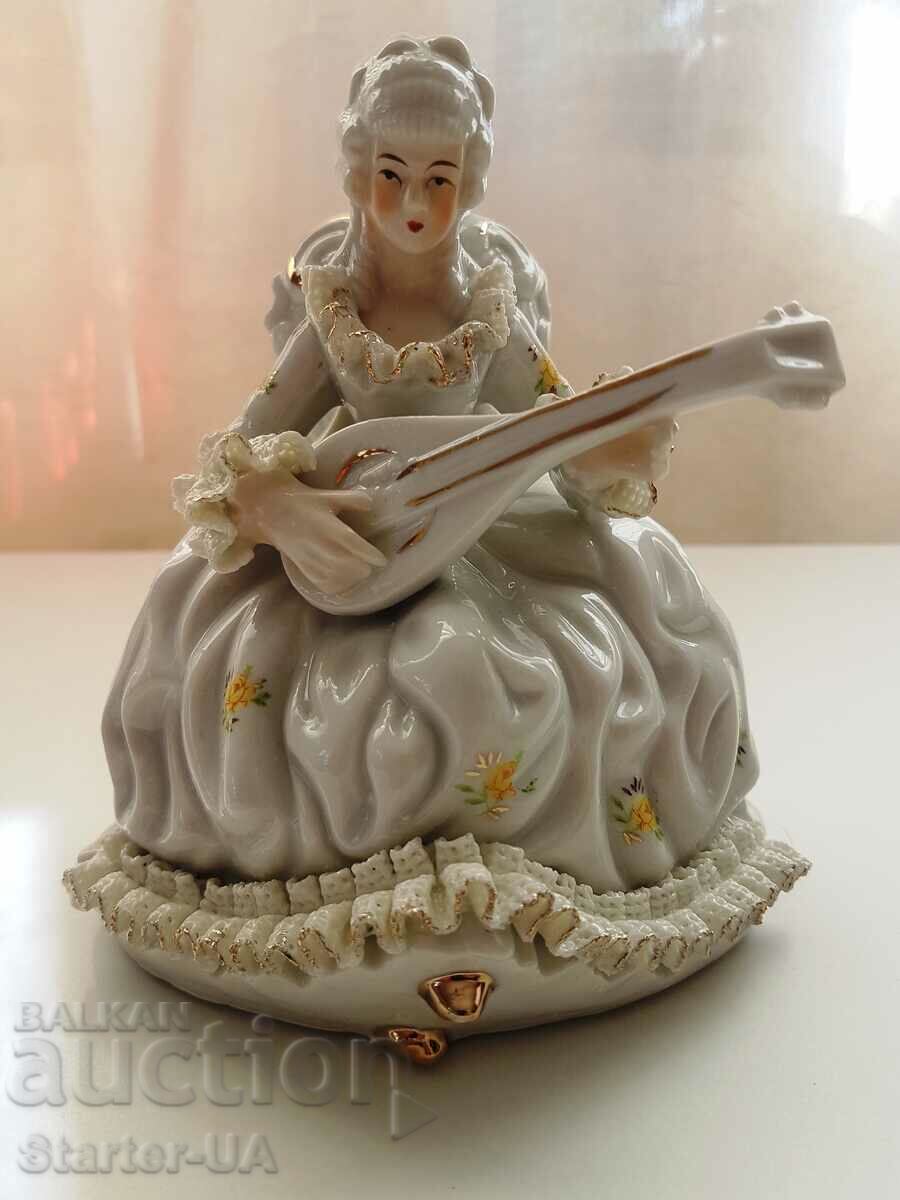 O frumoasă figură de porțelan a unei doamne cu un instrument muzical.