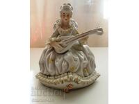 A beautiful porcelain figure of a lady with a musical instrument.