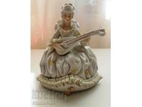 A beautiful porcelain figure of a lady with a musical instrument.