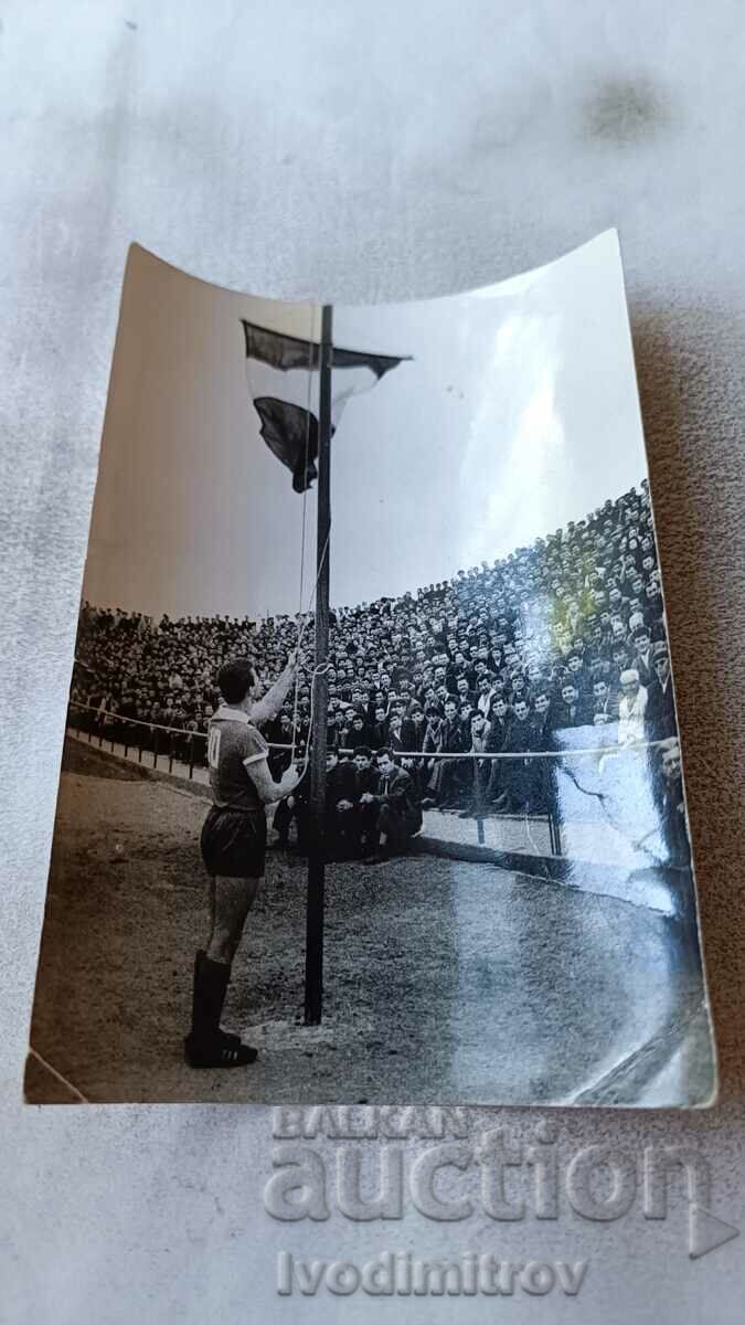Φωτογραφία Ένας ποδοσφαιριστής υψώνει μια εθνική σημαία σε ένα γήπεδο ποδοσφαίρου