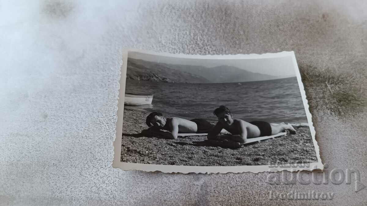 Photo Two men lying on the beach