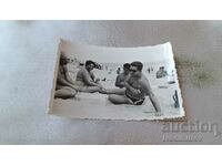 Photo Three men and a woman playing cards on the beach