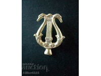 Lyre badge shaped with swan heads.