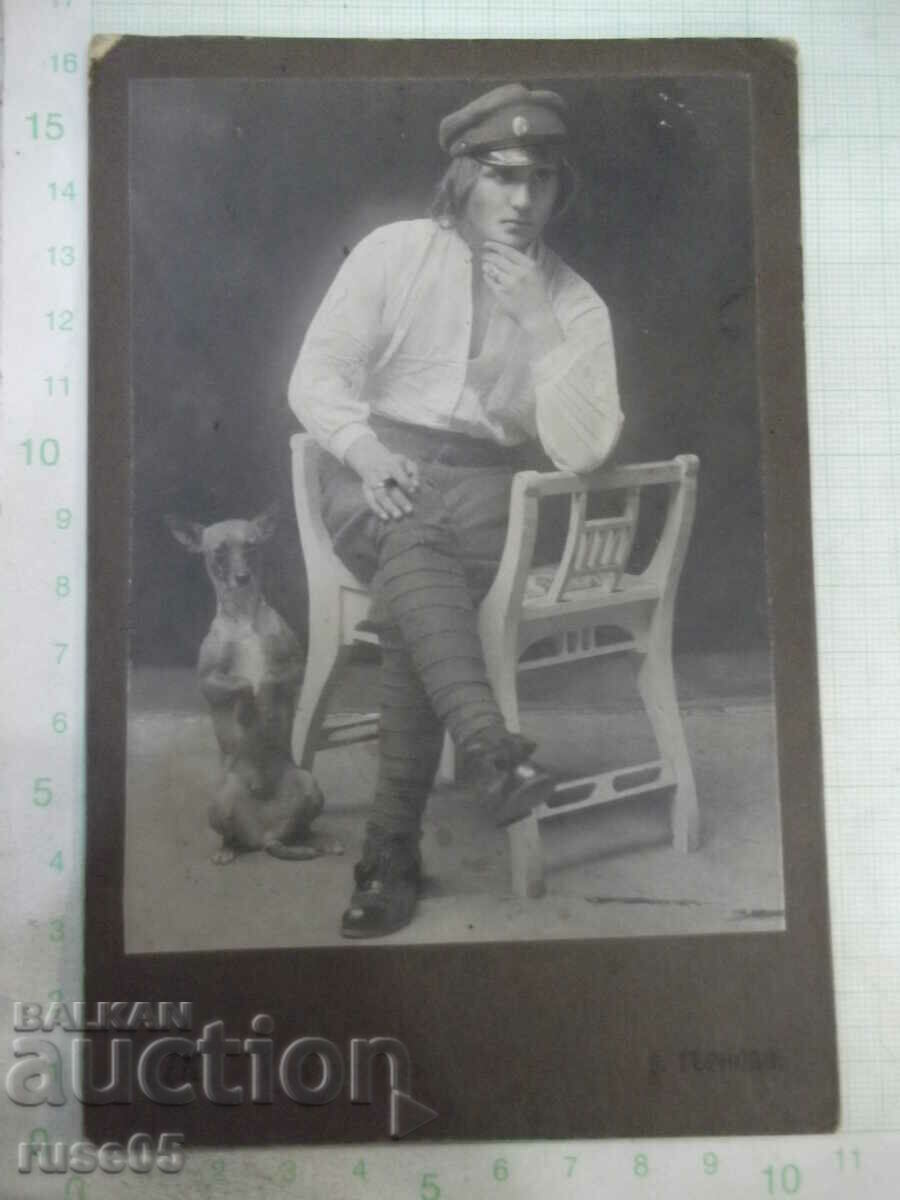 Old photo of a pensive man with a dog on a cardboard chair