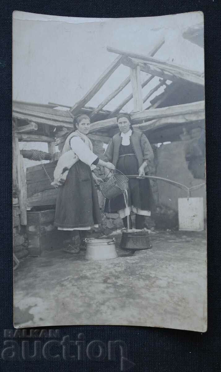 Women scoop water from a well