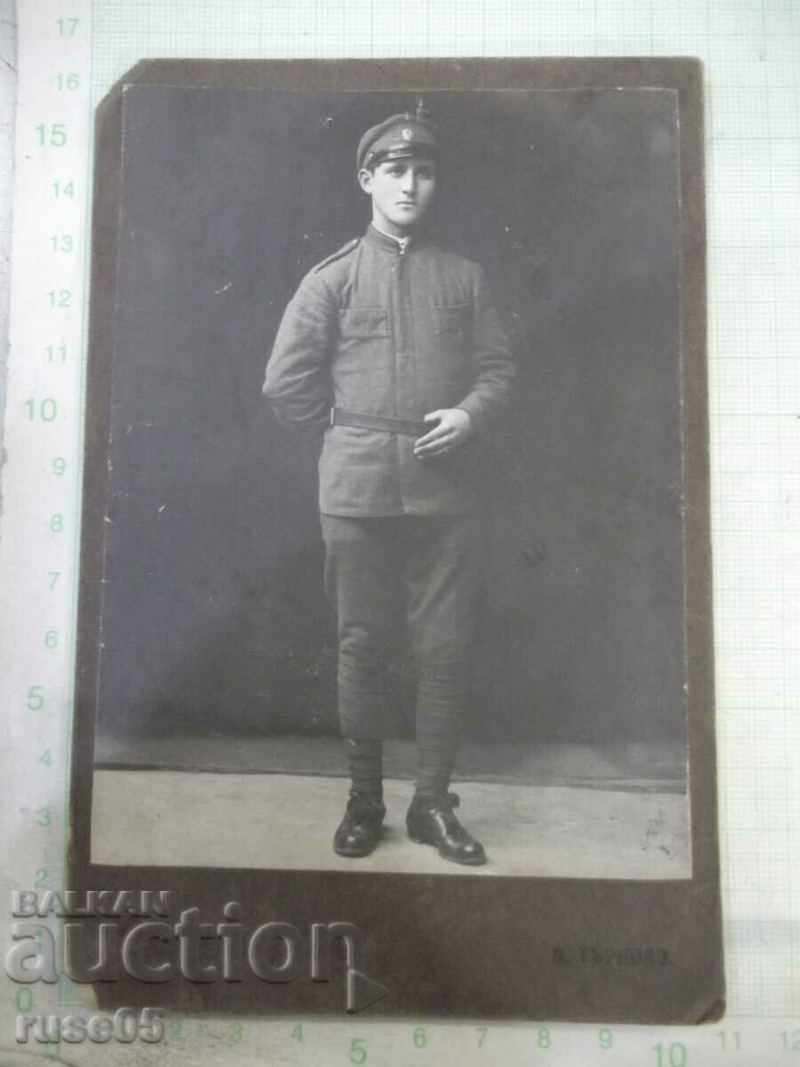 Old cardboard picture of a man in uniform with his hand on his belt