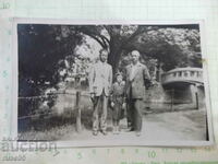 Old photo of two men and a little girl in front of a bridge