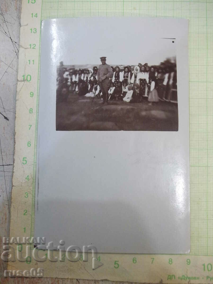 Old photo of women in costumes behind a military