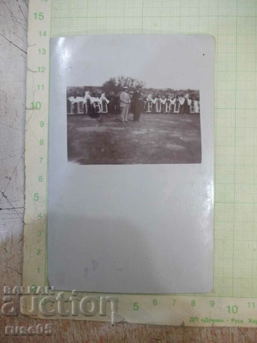 Old photo of women in costumes behind two civilians