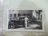 Old photo of a man in front of a house next to a car