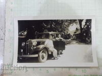 Old photo of a family in front of a house next to the car