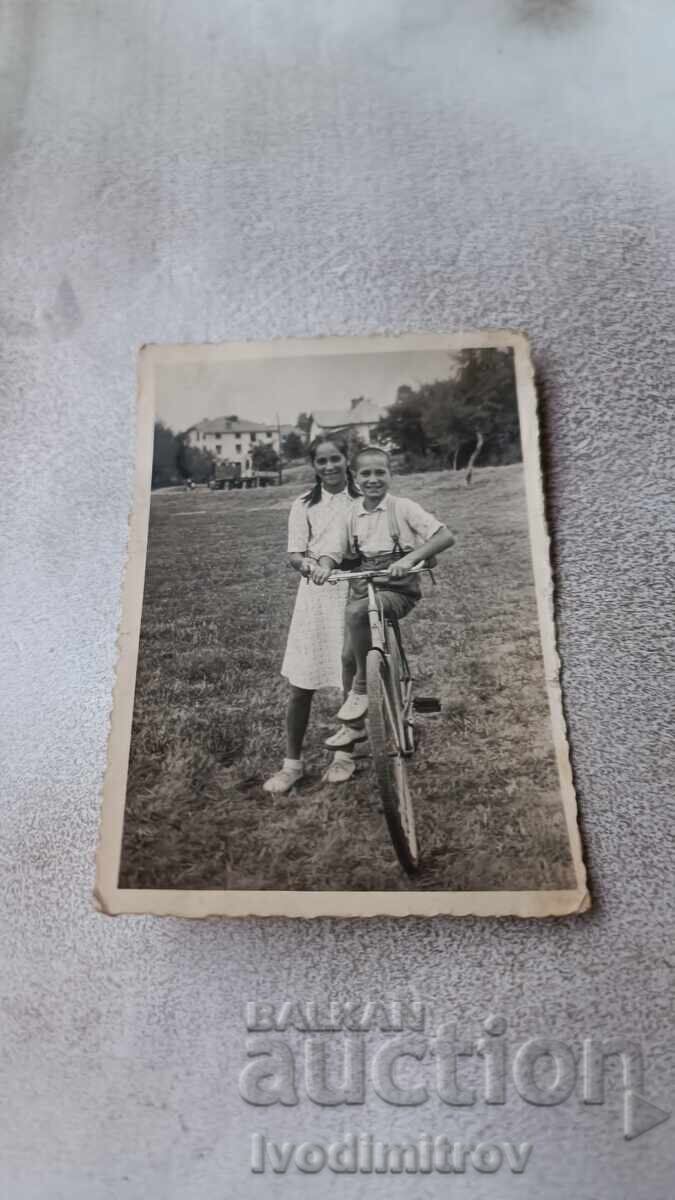 Foto Fată și băiat cu bicicleta retro pe iarbă