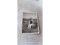 Photo Young girl sitting on a stone in the sea