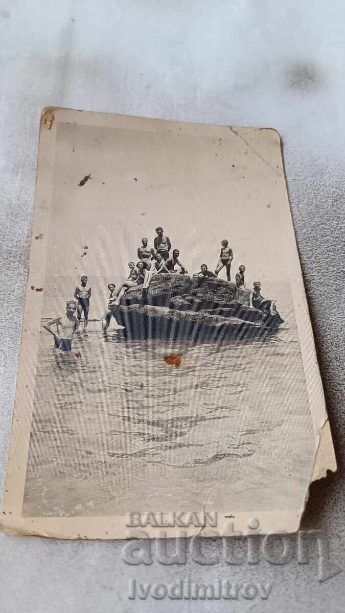 Photo of a young man and a young woman on a rock in the sea