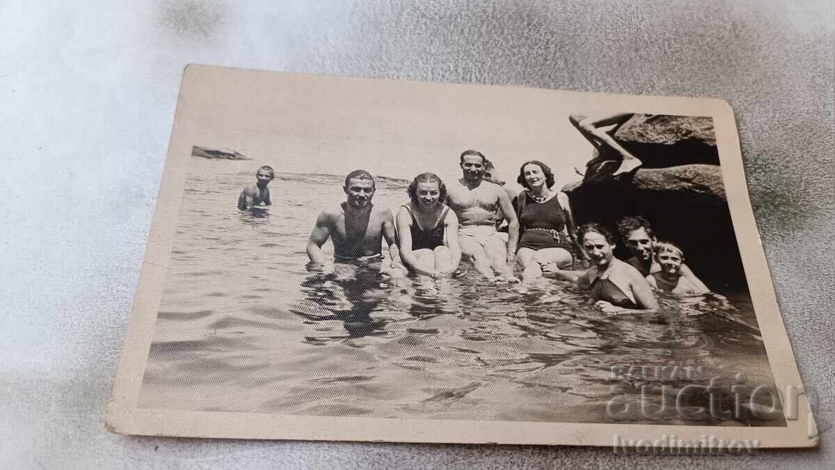 Fotografie Bărbați, femei și copii lângă o stâncă în mare