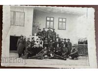 Military and civilians in front of a house