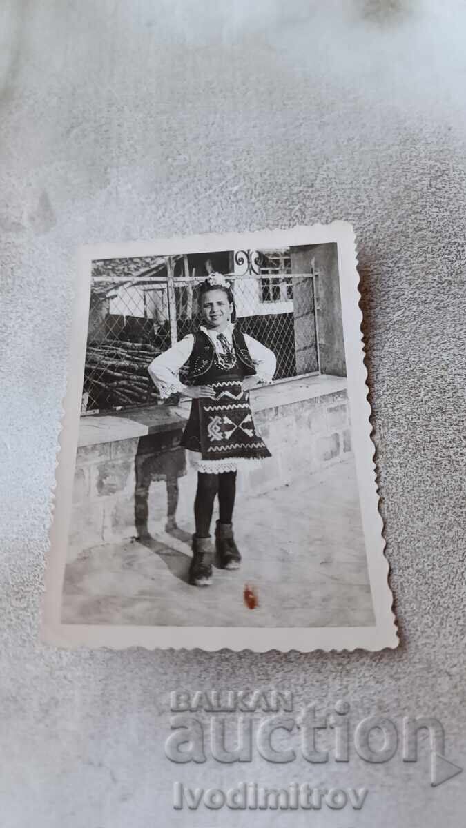 Φωτογραφία Νεαρό κορίτσι με λαϊκή φορεσιά στο πεζοδρόμιο