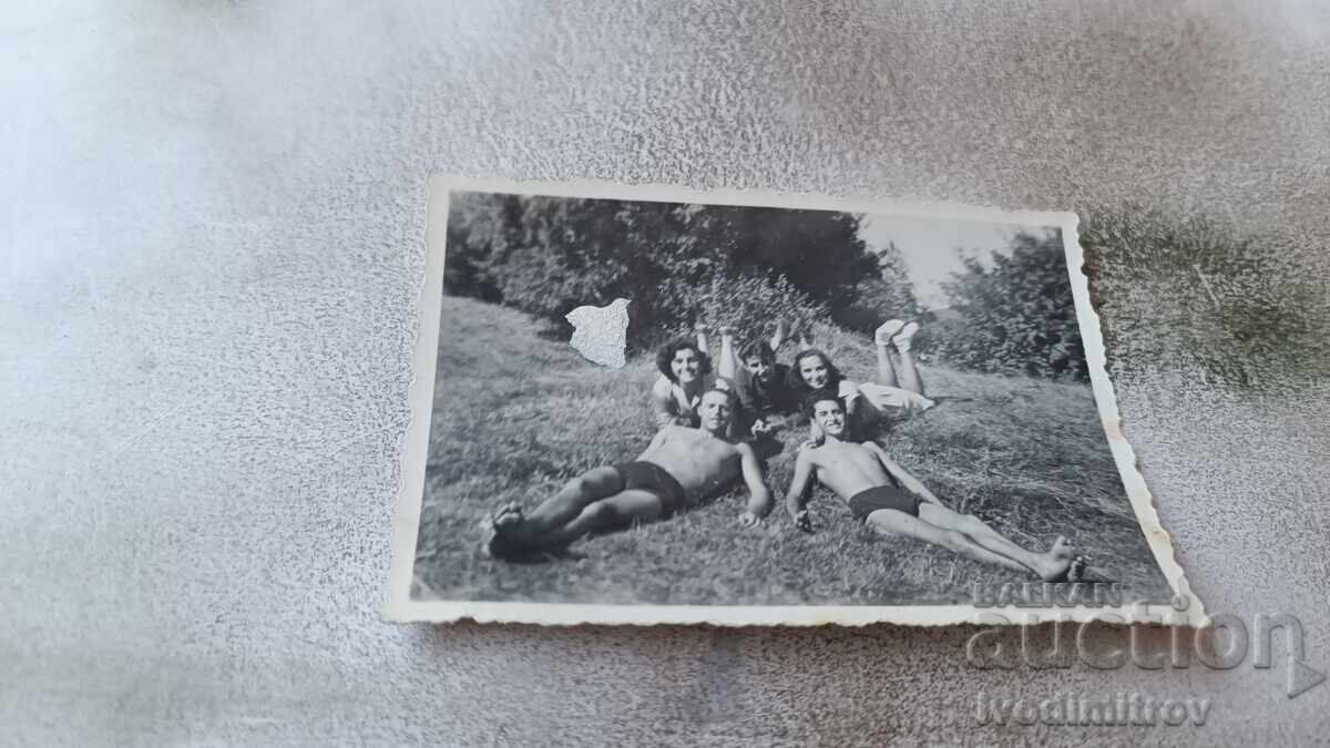 Photo Young men and women lying on the grass