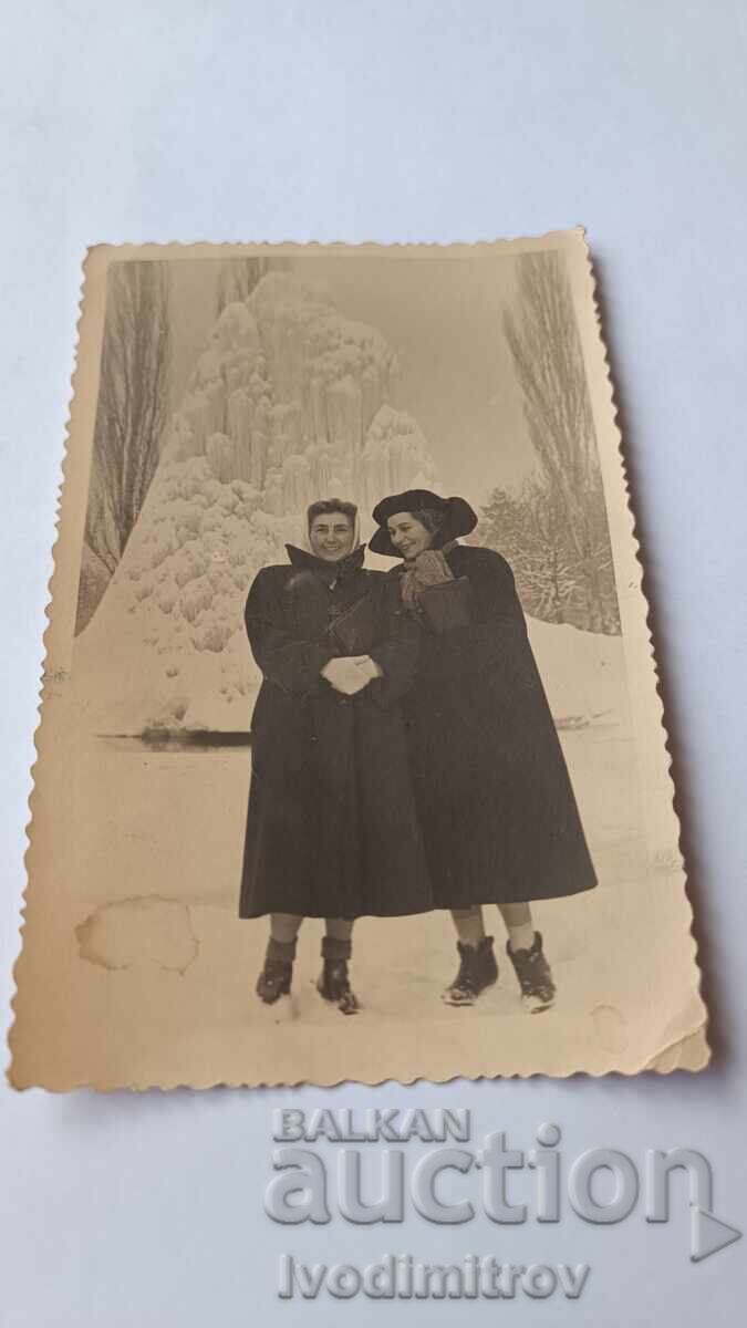 Photo of Two Young Women in Front of a Frozen Fountain in Winter