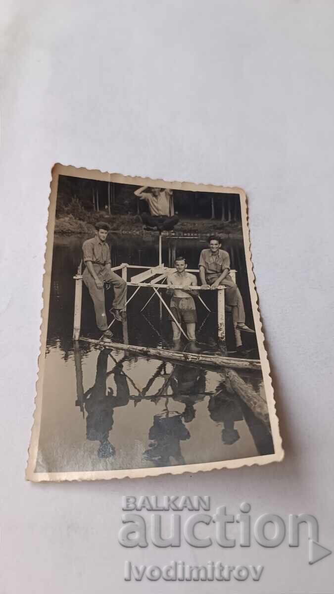 Φωτογραφία Τέσσερις νέοι άνδρες σε ξύλινη κατασκευή στο ποτάμι