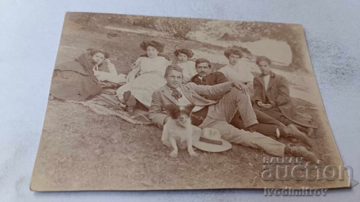 Photo of Young Men and Women with a Dog in a Meadow Photo of Young Men and Women with a Dog in a Meadow