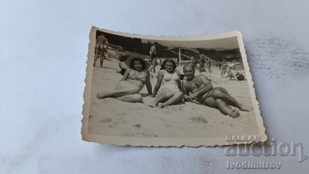 Fotografie cu un bărbat și două femei pe plajă Fotografie cu un bărbat și două femei pe plajă