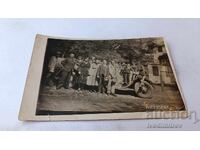 Fotografie cu bărbați, femei și copii în fața unei mașini retro