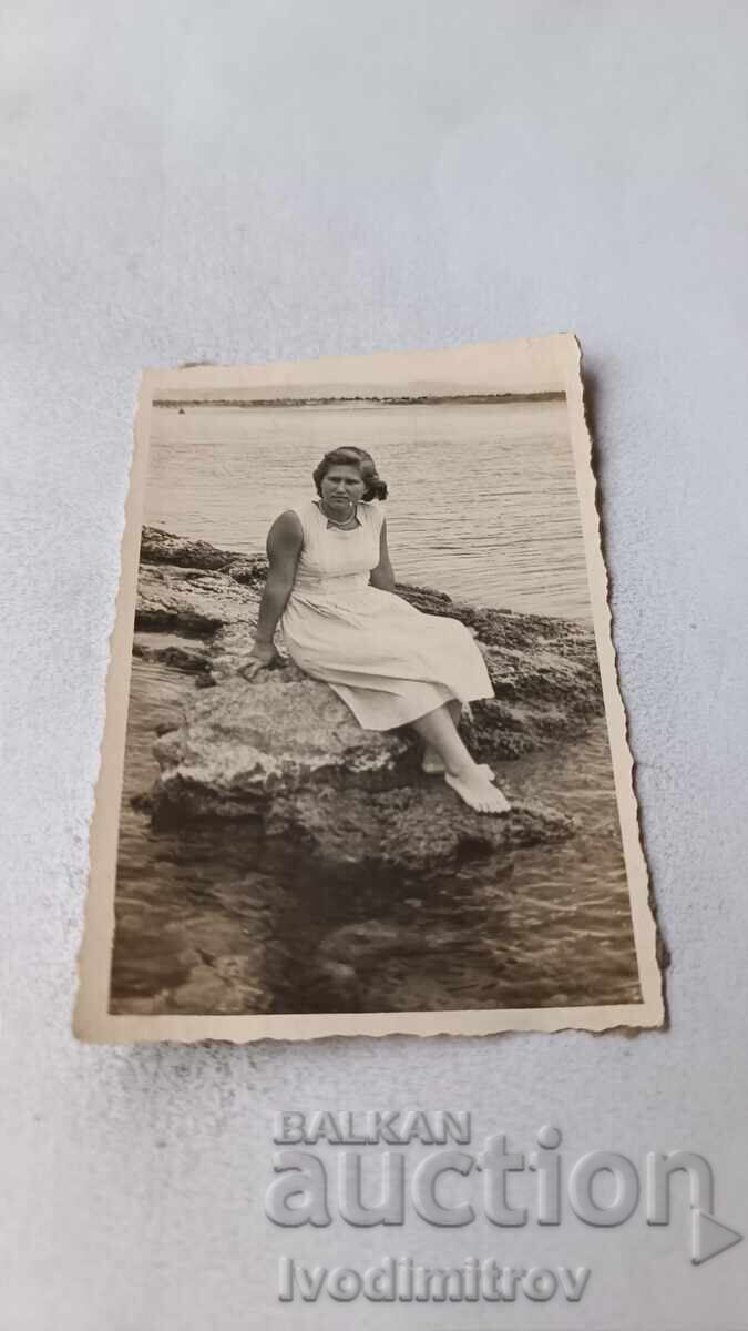 Photo of a woman sitting on a rock by the sea
