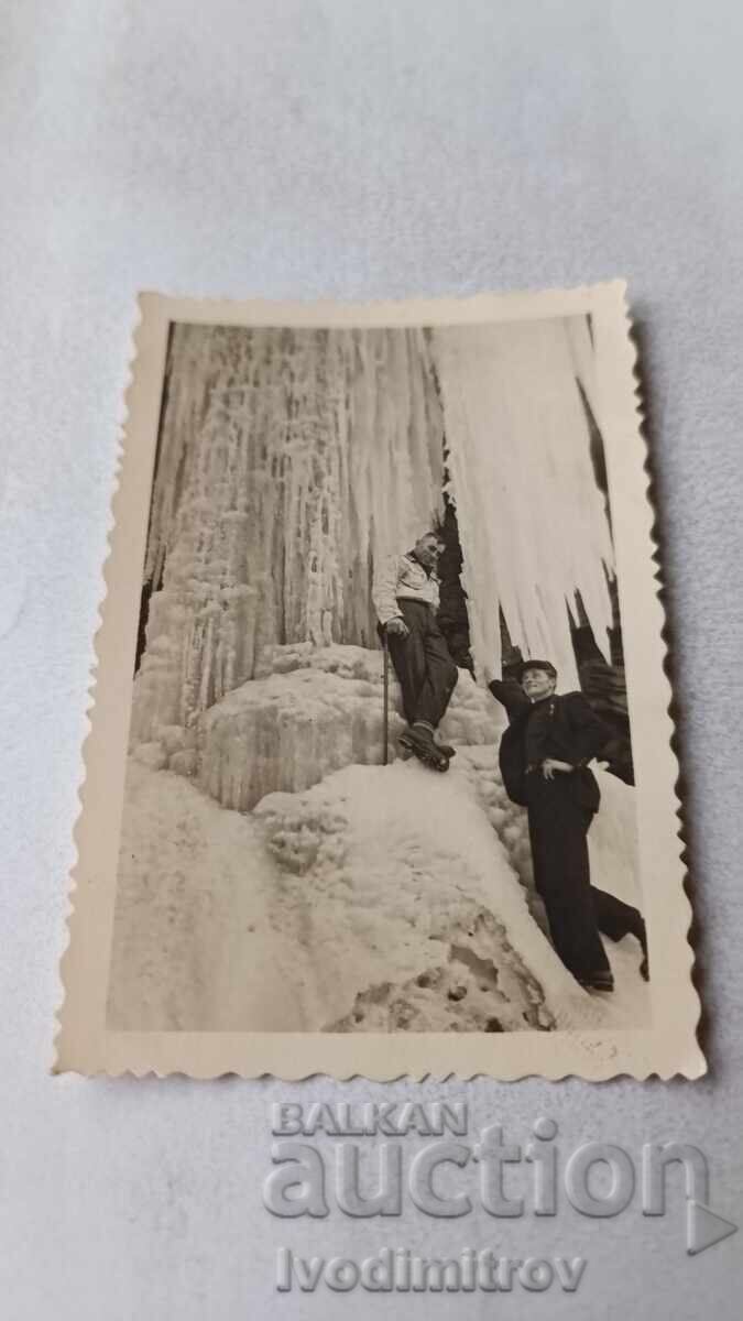 Φωτογραφία Δύο ανδρών δίπλα σε παγωμένο καταρράκτη