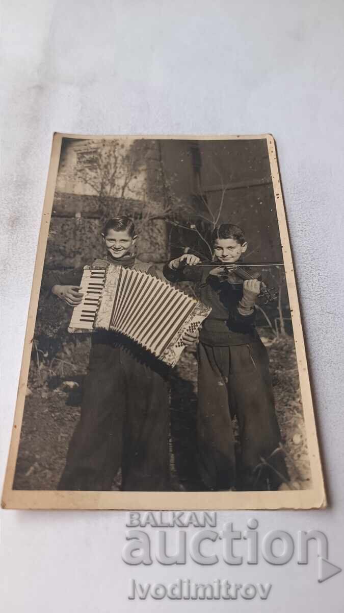Fotografie Doi băieți cu acordeon și vioară susțin un concert