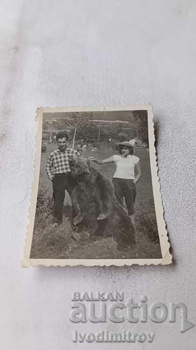 Φωτογραφία Άνδρας και γυναίκα δίπλα σε μια αρκούδα στο πάρκο