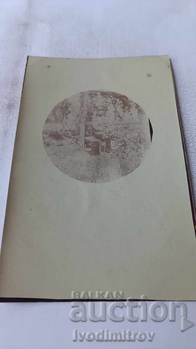 Fotografie Ofițer șezând pe bancă sub viță-de-vie Fotografie Ofițer șezând pe bancă sub viță-de-vie