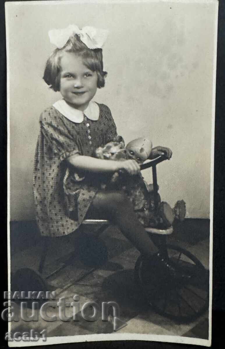 Момиченце на триколка с куклите си