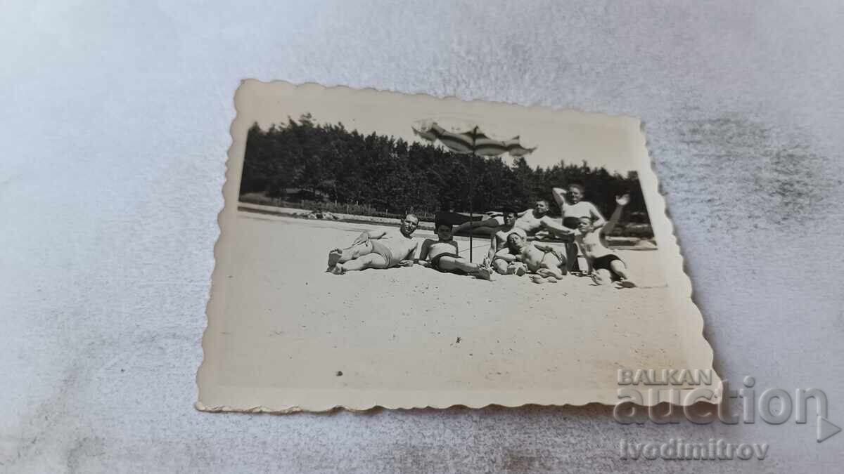 Photo: Men and Young Men Under Umbrella on the Beach Photo: Men and Young Men Under Umbrella on the Beach
