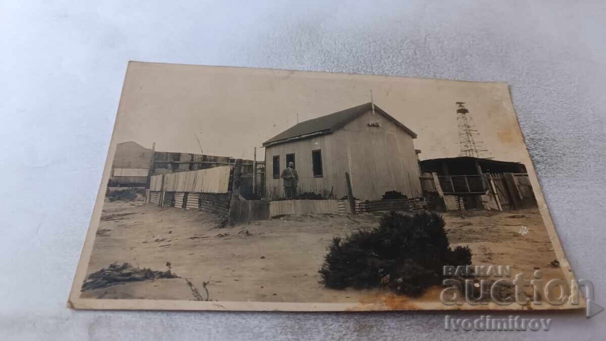 Photo: Man in front of a one-story building, 1930