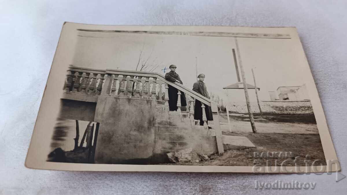 Photo of Two Young People on a Bridge Over a River