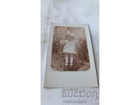 Fotografie Băiețel cu rochiță albă șezând pe un scaun împletit