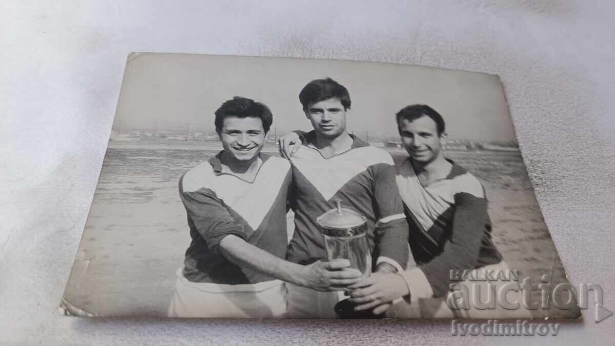 Fotografie cu trei fotbaliști ținând un trofeu