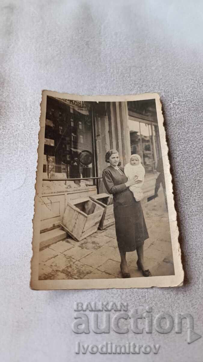 Fotografie Sofia Femeie cu bebeluș în fața a două magazine